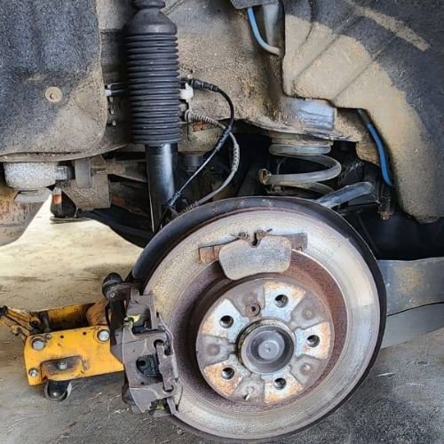 Exposed brake disc and caliper with removed brake pads resting on the disc.