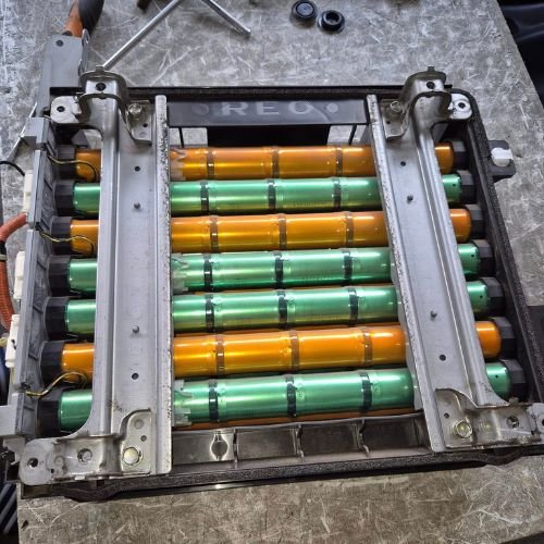 Hybrid battery pack with green and orange cylindrical cells exposed.