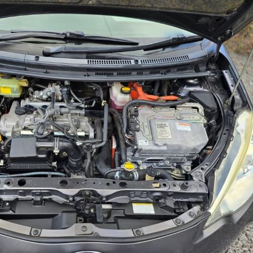 Hybrid car engine bay with inverter unit and orange high-voltage cables.