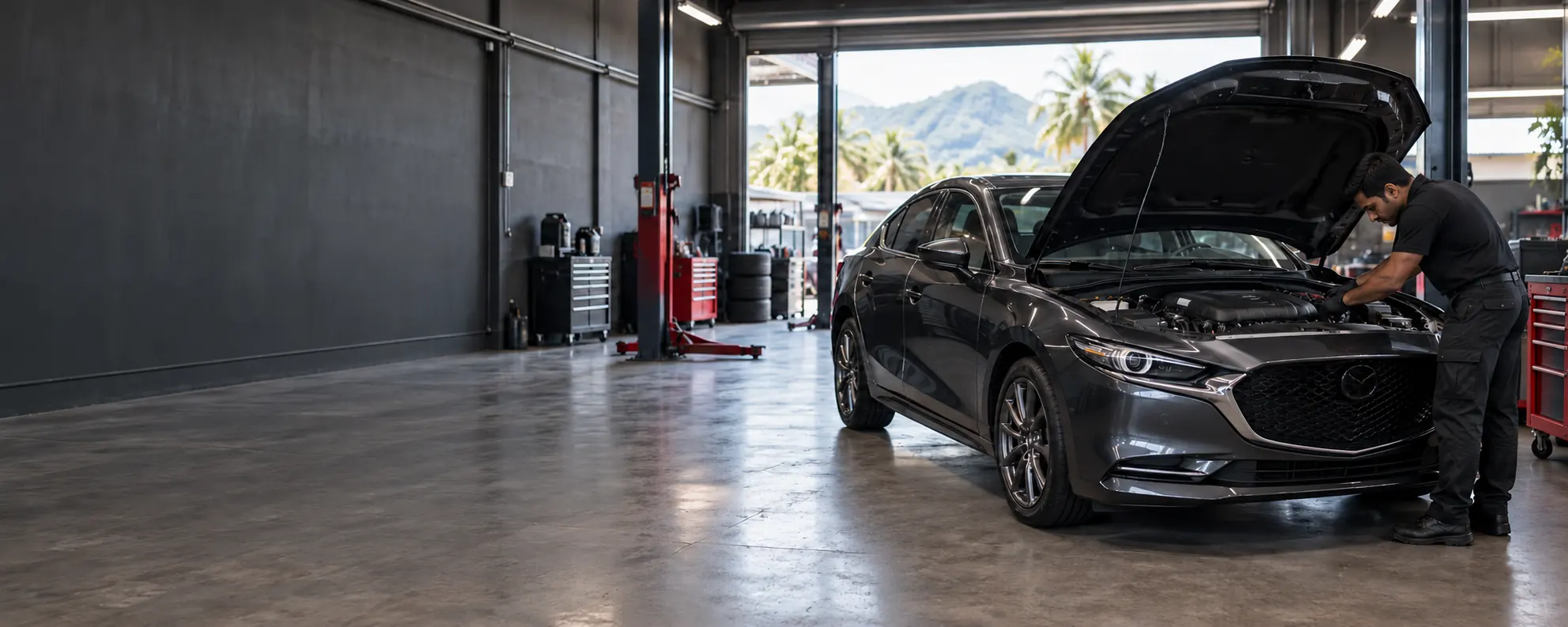 A car mechanic is working on a Mazda 3 in a garage