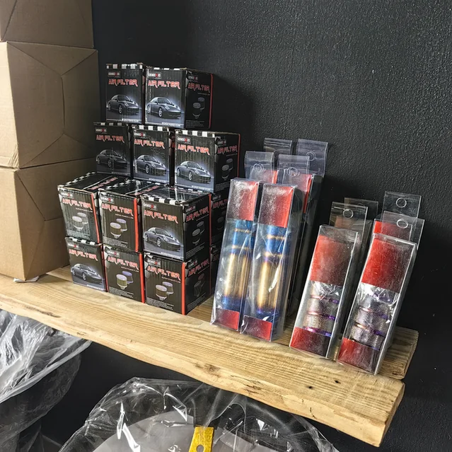 Boxed aftermarket air filters and packaged car accessories displayed on a wooden shelf.