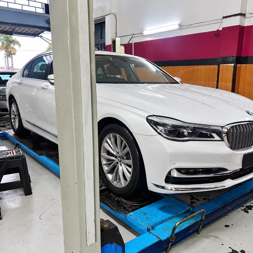White BMW 7 Series positioned on a blue workshop lift.