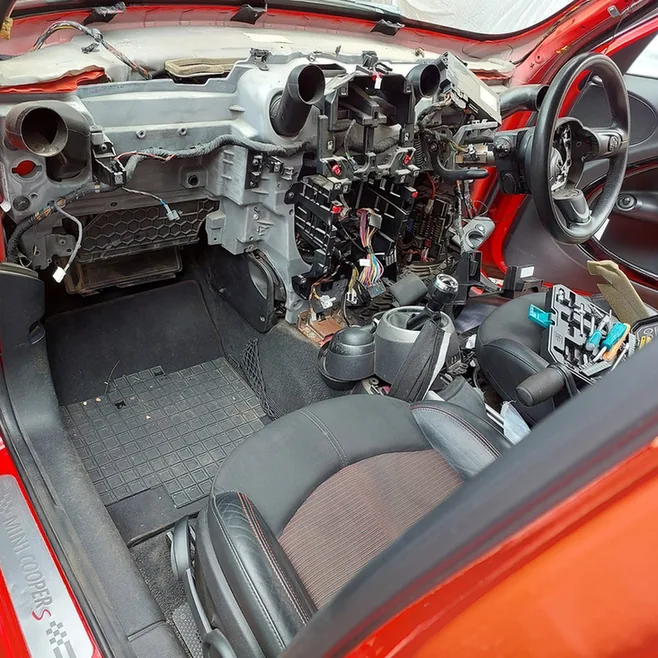 Mini Cooper dashboard dismantled for electrical wiring repairs.