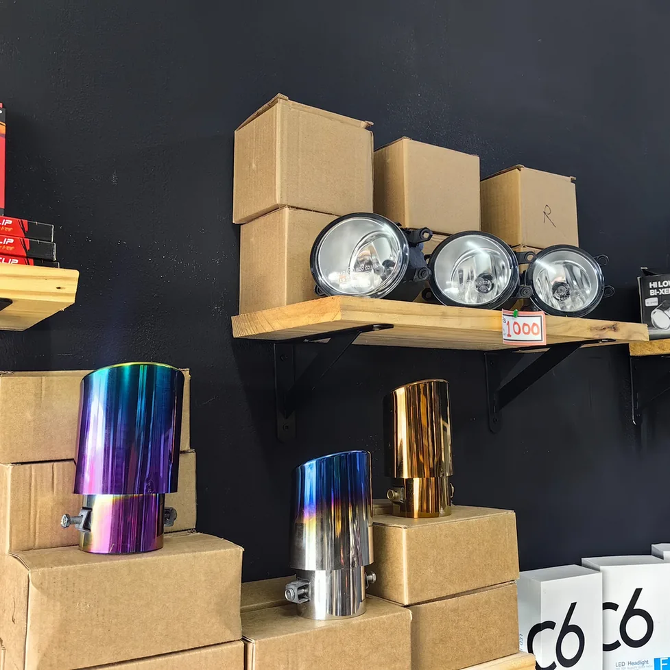 Round fog lights and metallic exhaust tips displayed on shop shelves.