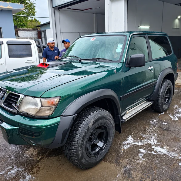 Dark green Nissan Patrol with black wheels outside the workshop.