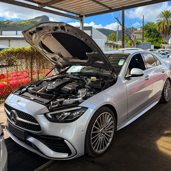 Silver Mercedes-Benz with its bonnet open, showing the engine bay above an inspection pit.
