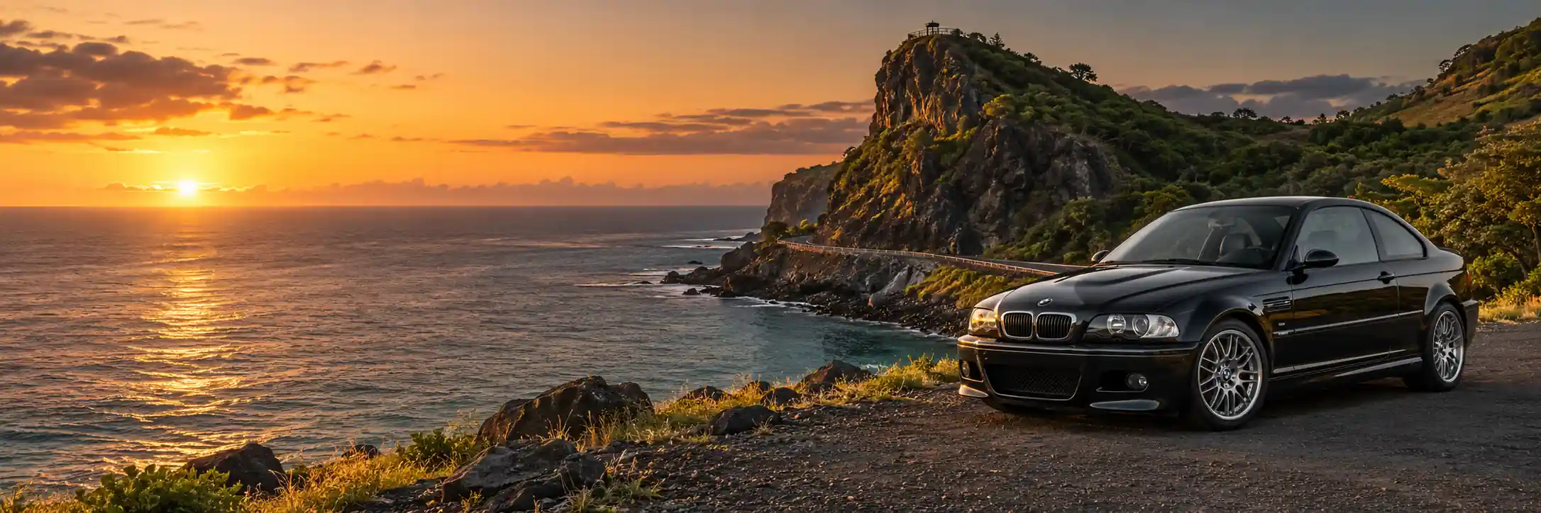 Black BMW E46 M3 beside the coastal road at Macondé viewpoint, Mauritius, at sunset.