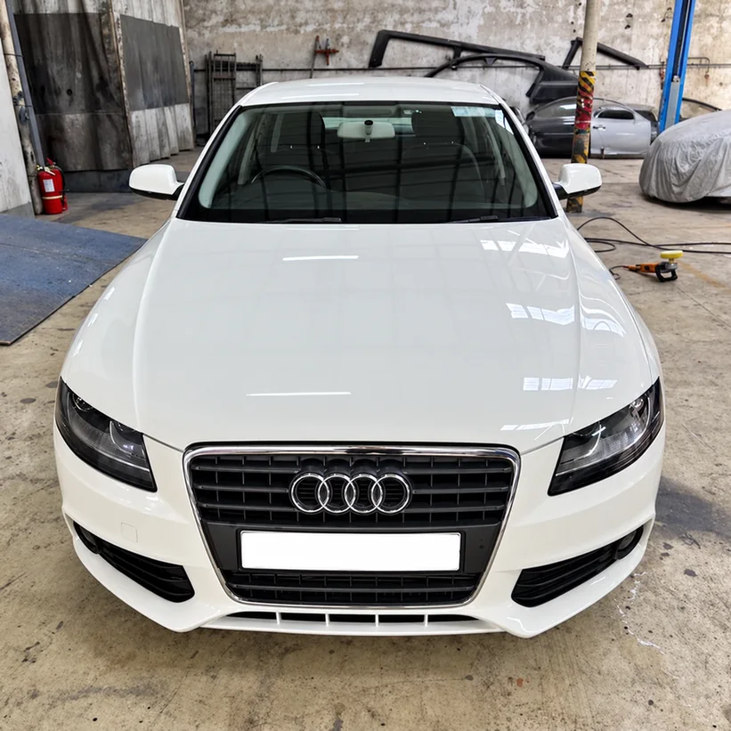 Front view of a white Audi inside an automotive workshop.